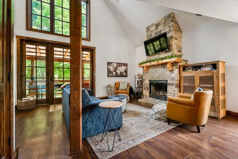 Sitting area beside the stone fireplace with a velvet accent chair and vaulted ceiling