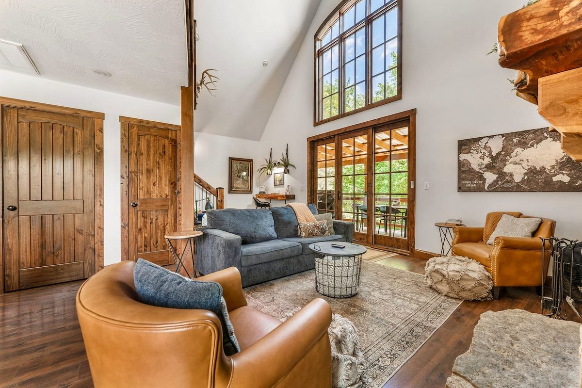 Leather armchair and sofa beneath the cabin’s dramatic two-story window wall