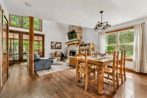 Open living and dining space anchored by the stone fireplace and timber accents