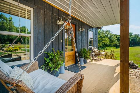 Hanging porch swing beside potted plants on the covered front porch