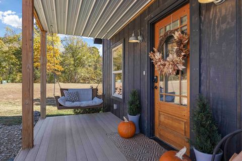 Front porch with a swing, autumn decor and the cabin’s arched wooden door